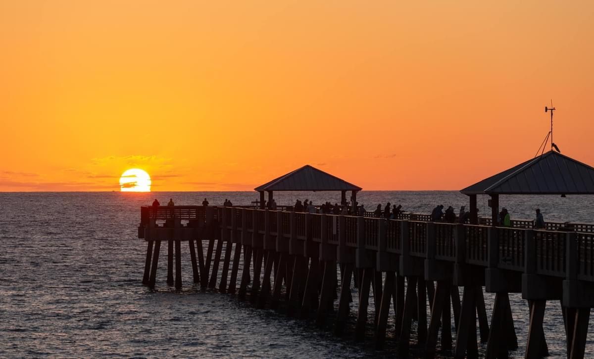 Juno Beach pier at sunset with silhouettes